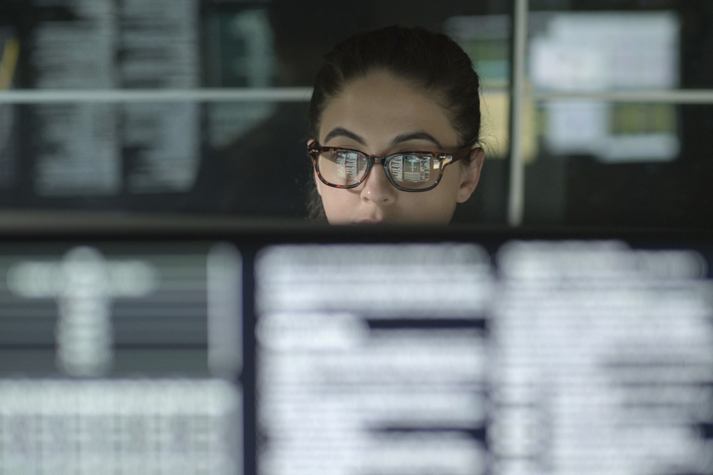 Woman wearing eyeglasses shown working from behind a computer